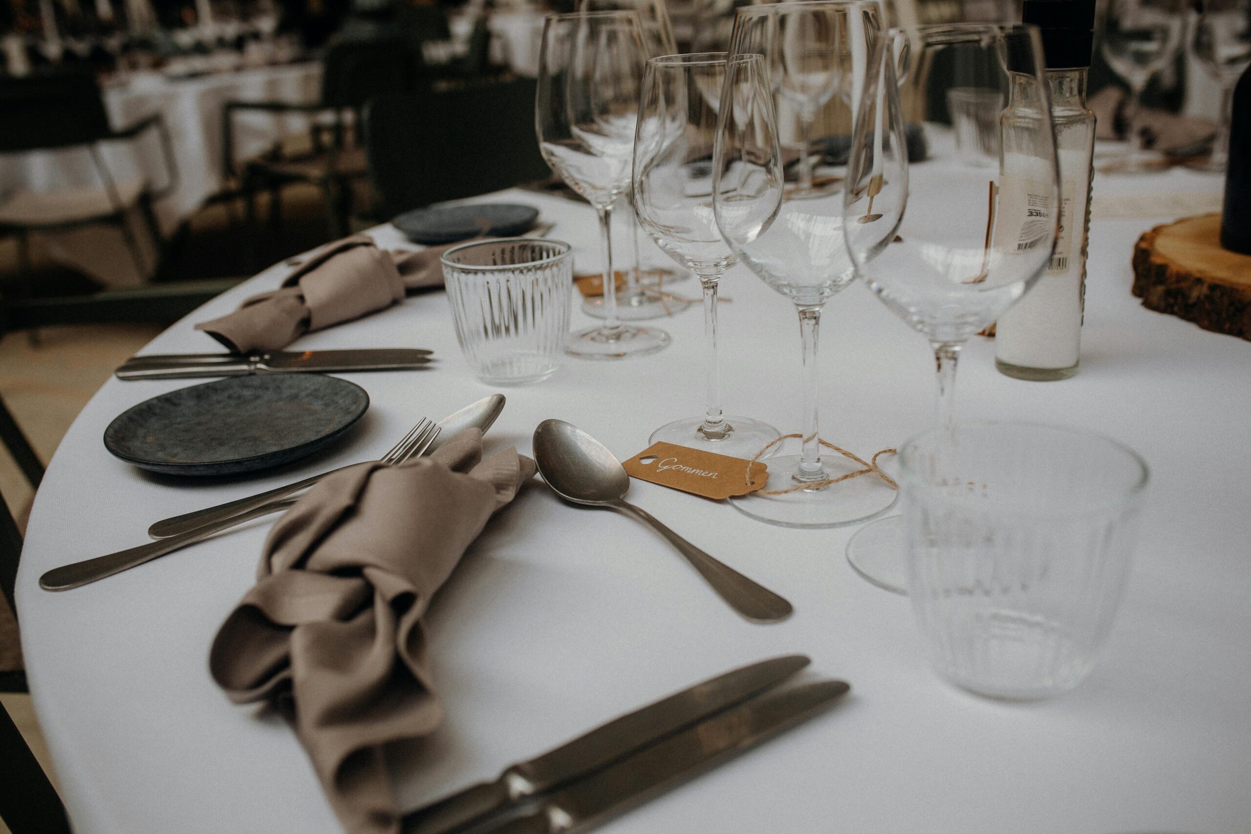 A sophisticated table setup featuring glasses, utensils, and napkins on a white tablecloth.