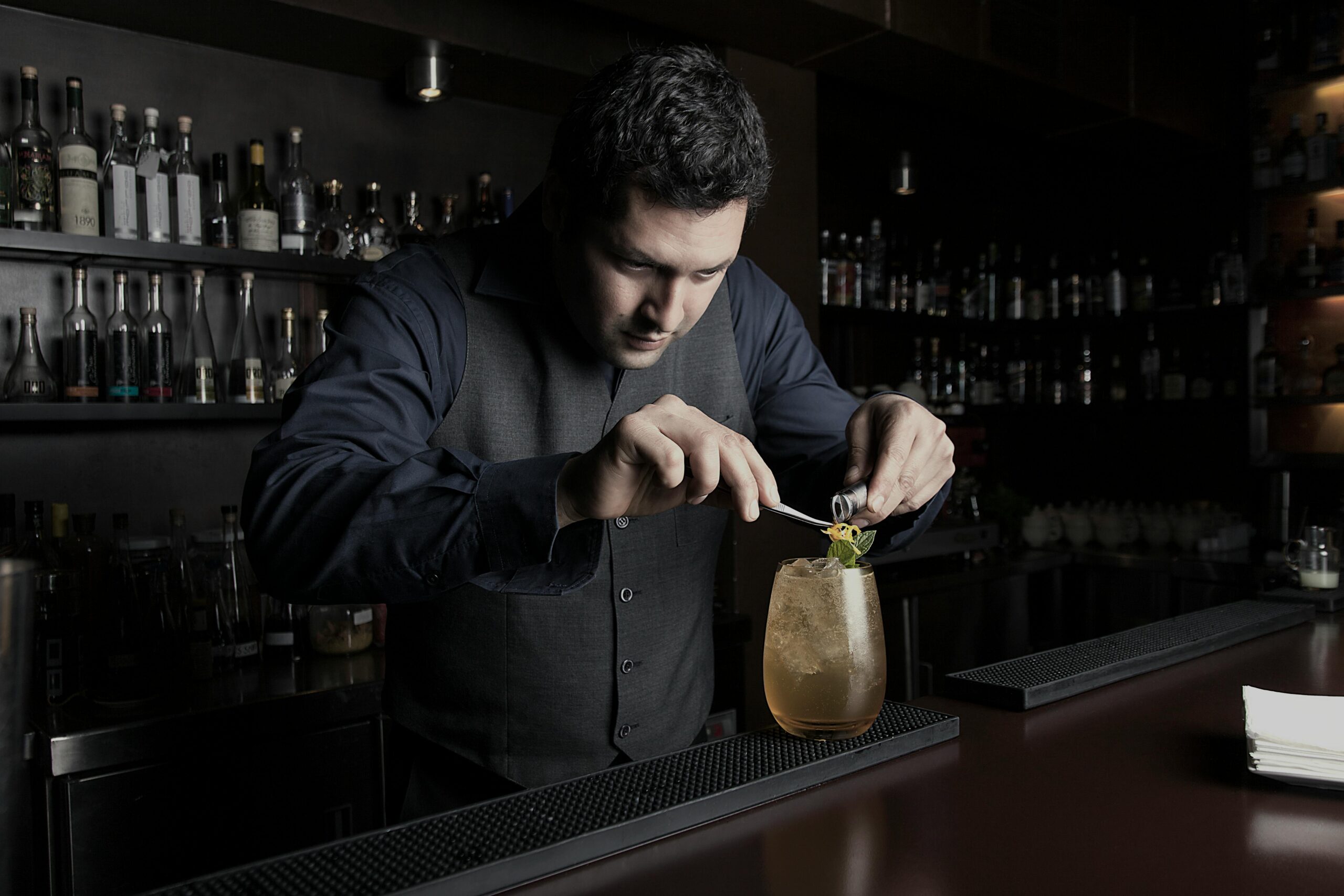 A skilled bartender in Lima prepares a cocktail with precision and style.