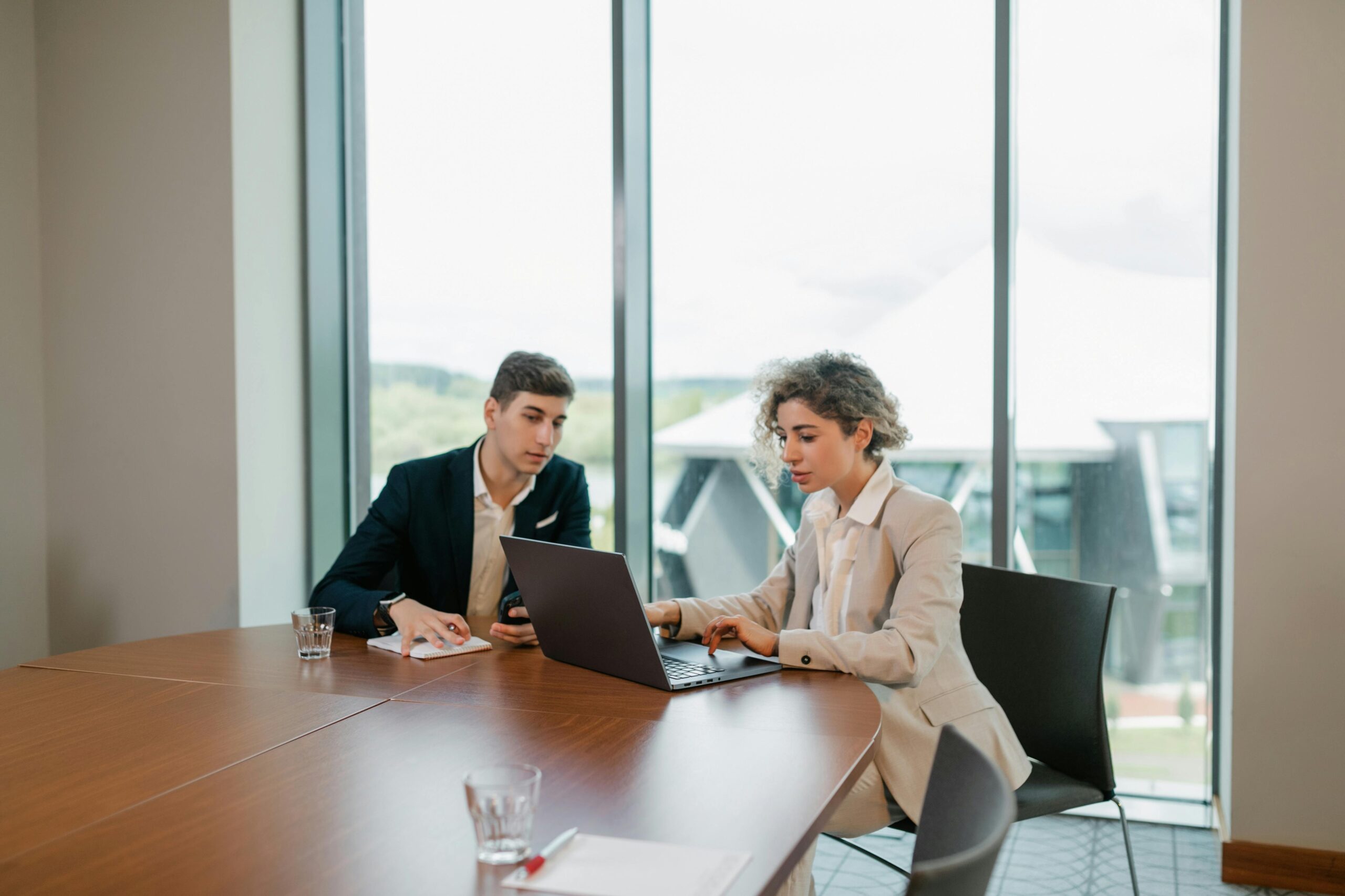 Two colleagues engaged in a business meeting in a well-lit modern office space.